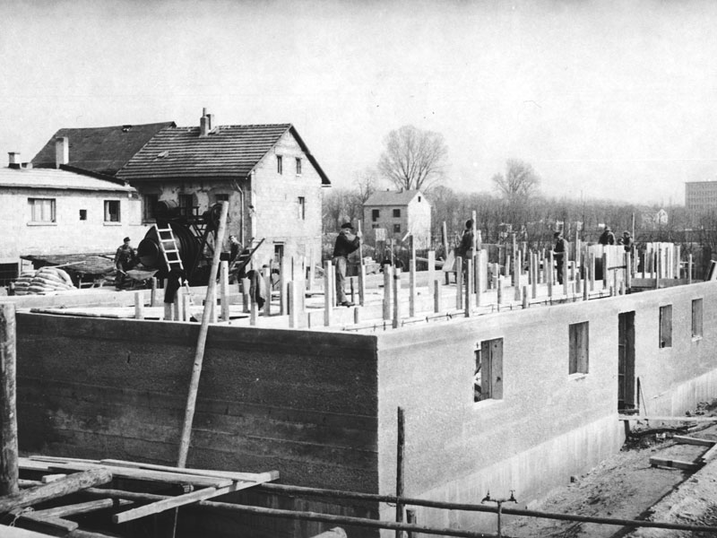 GSG_90Jahre_02_800x600px_sRGB Historische Schwarz-Weiß-Aufnahme einer Baustelle mit Arbeitern beim Errichten eines Gebäudegrundrisses