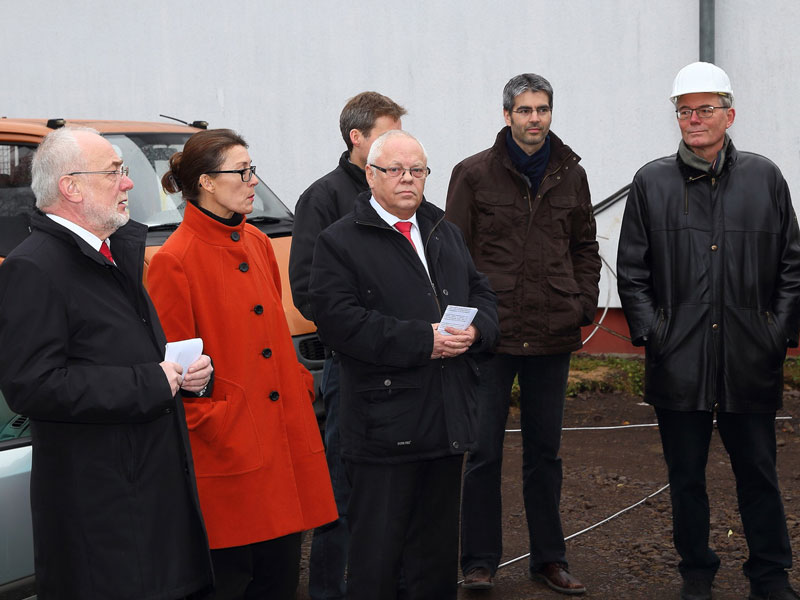 GSG_Chronik_02_800x600px_sRGB Eine Gruppe von Menschen in Winterkleidung steht im Freien vor einem Baugelände mit einem Bauleiter mit Schutzhelm
