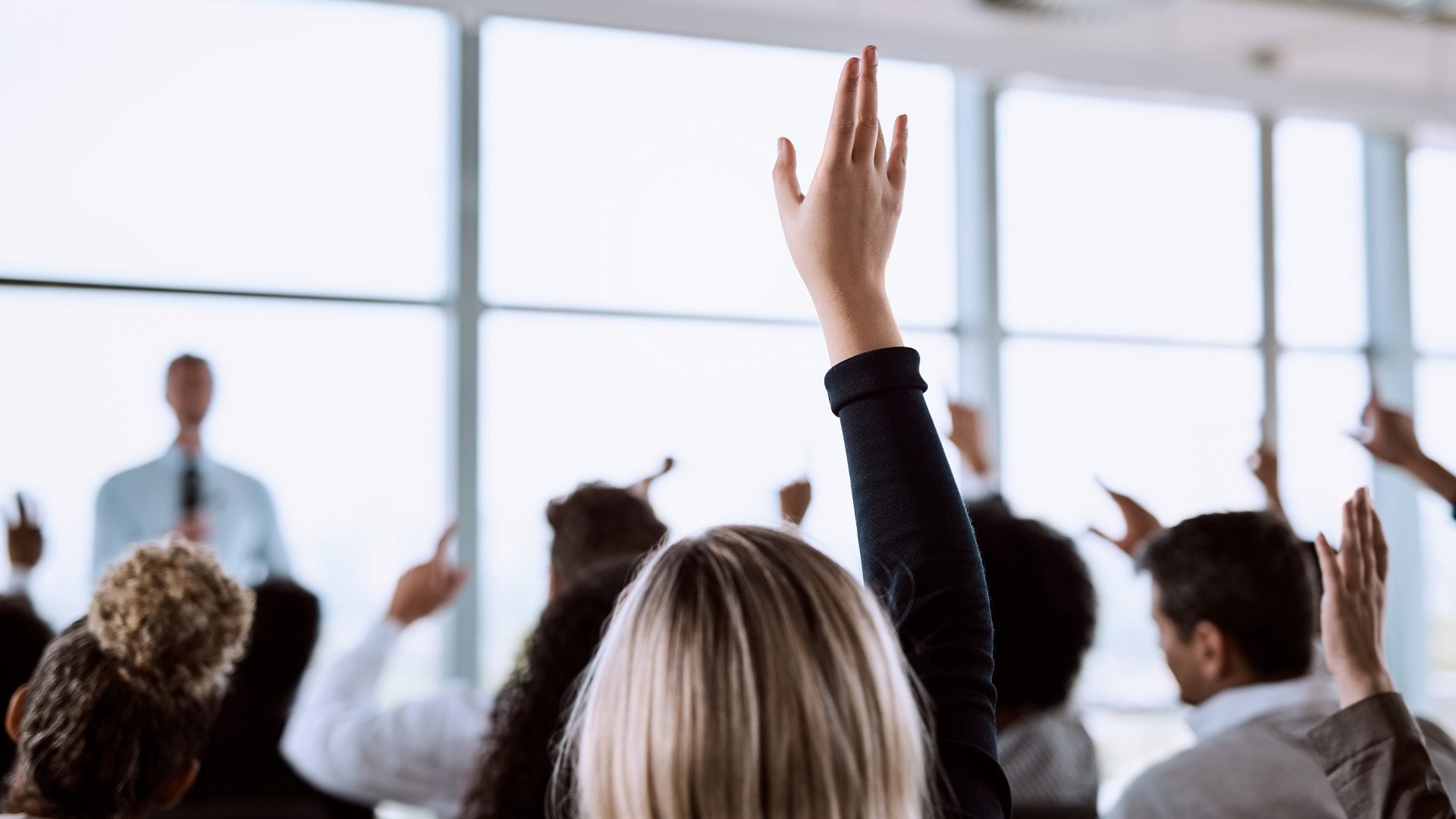 Publikum hebt bei einem Gesprächsabend die Hand um eine Frage an den Redner zu stellen