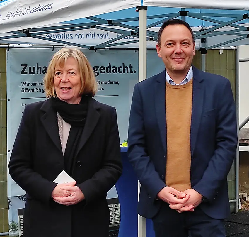 Eine Frau und ein Mann stehen vor einem Informationszelt der GSG bei einer Sanierungsankündigung