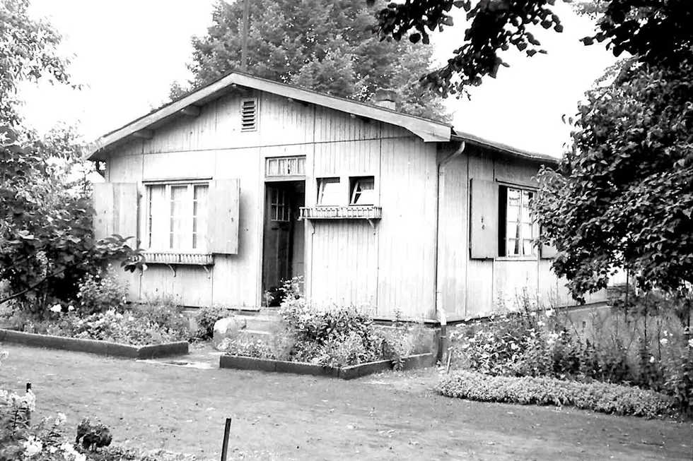 GSG-100-Jahre-Schweizer-Haeuser Schwarzweissaufnahme eines historischen Schweizer Hauses aus Holz mit Garten im Vordergrund