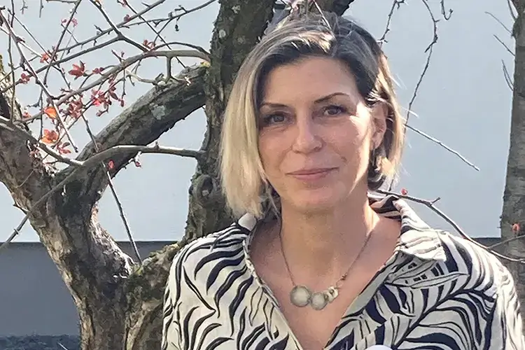Alexandra Gras blickt freundlich in die Kamera vor einem Baum