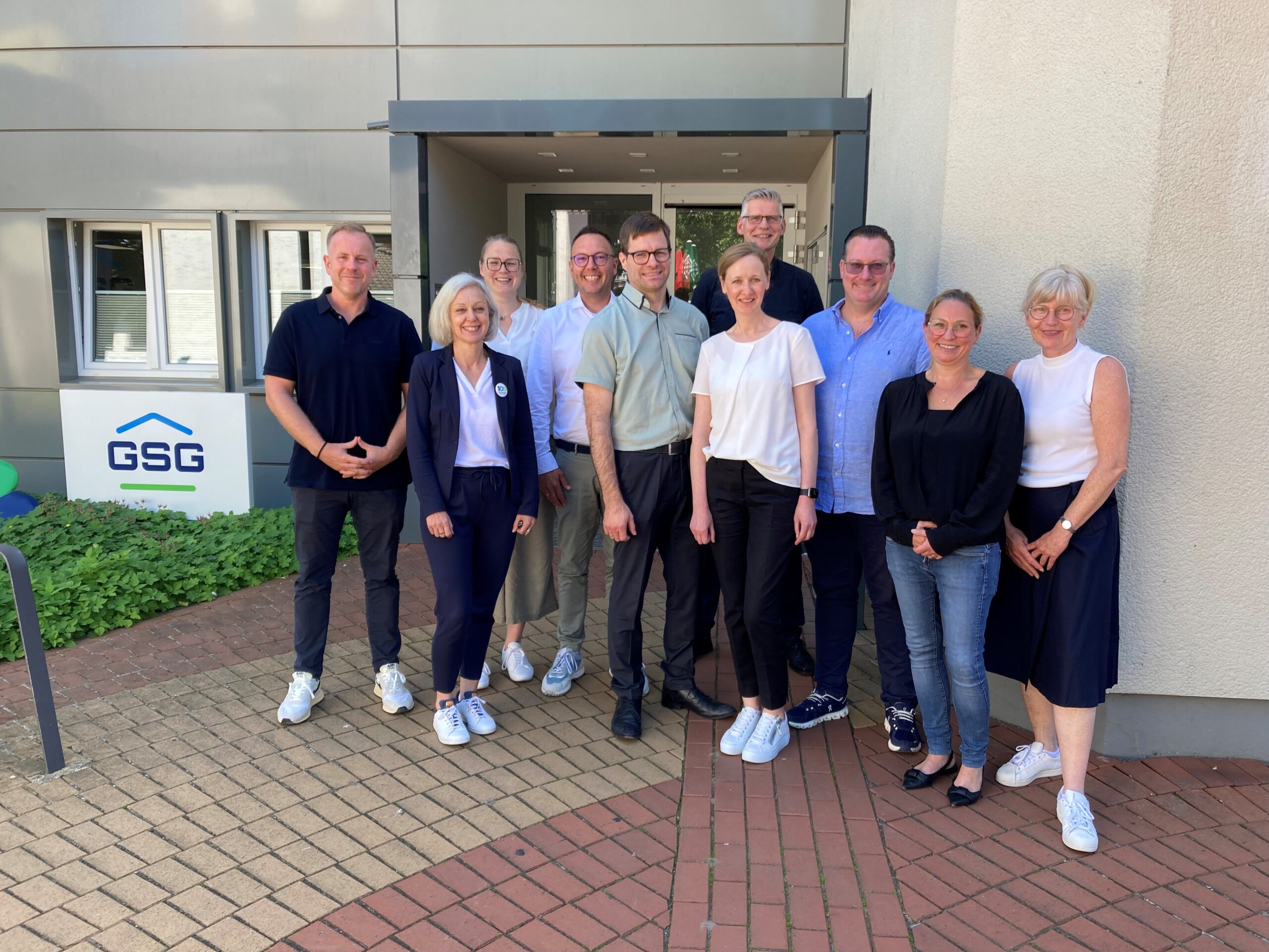 Gruppe von Mitarbeitern verschiedener Wohnungsunternehmen vor einem Firmengebäude