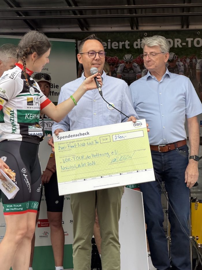 Drei Personen halten gemeinsam einen Spendenscheck der GSG über 2500 Euro für die Vor-Tour der Hoffnung