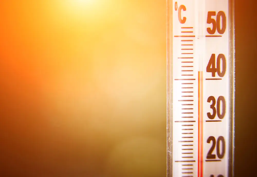 Ein Thermometer zeigt bei strahlendem Sonnenschein eine hohe Temperatur von fast 40 Grad Celsius an