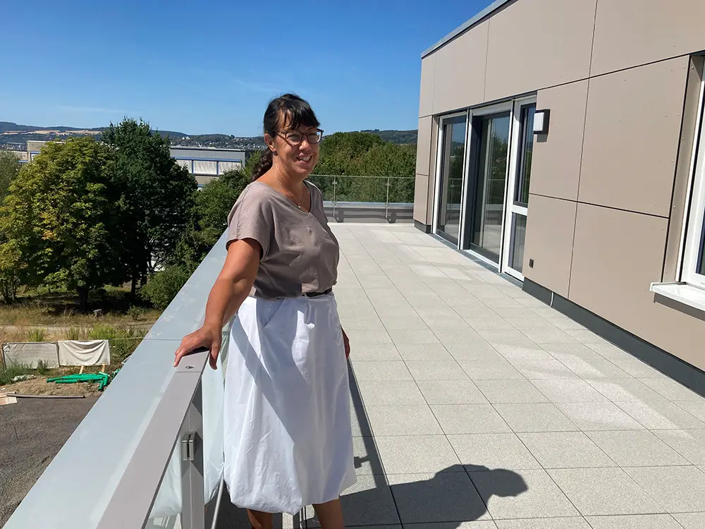 Neubau-Heddesdorfer-Berg-Natascha-Schmitz-GSG Eine Frau steht auf der Terrasse eines modernen Neubaus und blickt in die Umgebung